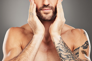 Image showing Beauty, skincare and body with a man model in studio on a gray background with an arm tattoo for wellness. Health, luxury and skin with a male touching his face for cleaning or natural bodycare