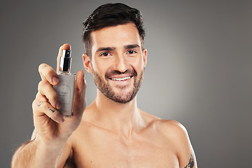 Image showing Man, face or body care cologne bottle on gray studio background for morning grooming routine, aroma fragrance or scent spray. Portrait, smile or happy male perfume model and parfume product container