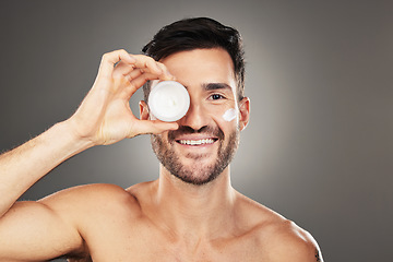 Image showing Face, skincare and product with a man model in studio on a gray background to promote beauty treatment. Portrait, container and antiaging with a handsome young male posing for wellness or care