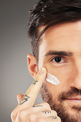 Image showing Man, face and cream for beauty, skincare and wellness with hand against a grey studio background with mockup. Male model with facial lotion on sunscreen lotion for skin health and protection from uv