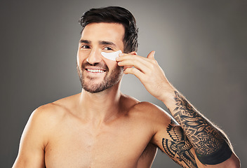 Image showing Skincare, face and man with eye patch on a gray studio background. Portrait, beauty and male model from Australia with facial product, cosmetics pads or collagen eye mask for hydration or anti aging.
