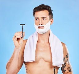 Image showing Shave, razor and man with shaving cream and towel for grooming, beauty and skincare against blue studio background. Clean, hygiene and face product in hand with fresh skin and hair removal mockup.