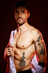 Image showing Fashion, sexy and portrait of a man in a studio with muscles, body and tattoos for body care or fitness. Handsome, young and edgy model from Canada posing with bare chest isolated by dark background.