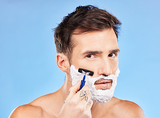 Image showing Facial, shave and razor portrait of man for hygiene, cleaning and self care routine for healthy skin. Wellness, health and face of model with beard foam on blue studio mock up for advertising.