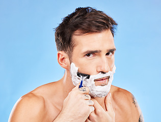Image showing Man, razor and shaving for haircare, grooming and hair removal for hygiene on a blue studio background. Portrait, man and beauty to shave beard or face with foam or soap for facial cleansing