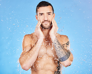 Image showing Water, cleaning and man washing face for skincare, wellness and health of body against a blue studio background. Shower, happy and portrait of a model with care for grooming, hygiene and skin