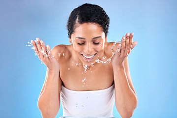 Image showing Black woman, cleaning face with water, skincare and wellness with smile against a mockup studio blue background. Female model washing face, beauty and happy for skin health, happiness or water splash