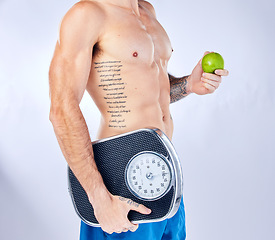 Image showing Body, scale and apple with a man in studio on a gray background for weightloss, diet or healthy eating. Fitness, tattoo and health with a male holding fruit while posing for a nutrition lifestyle