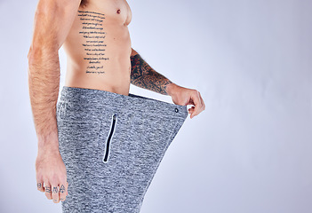 Image showing Lose weight, man and big trousers after exercise, fitness and workout against grey studio background. Health, male and with pants showing size, training progress and success with diet and body care.