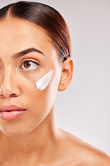 Image showing Face, beauty and skincare with a model black woman in studio on a gray background for skin hydration. Costmetics, antiaging and moisturizer with an attractive young female with cream on her cheek