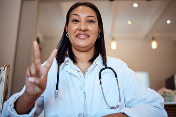 Image showing Doctor, black woman and peace sign in video call, hospital and smile with happiness, proud and medical job. Woman, nurse or happy medic in clinic, office or telehealth in healthcare with hand signal
