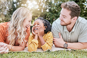 Image showing Family, adoption and picnic on blanket in park with mother, father and black girl in nature, relax and happy. Diversity, kid and parents relaxing on grass in the yard, enjoy summer with love or smile