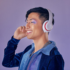 Image showing Music, makeup and cyberpunk with an asian man model in studio on a purple background for lgbt freedom. Future, happy and fashion with a handsome young androgynous male streaming or listening to audio