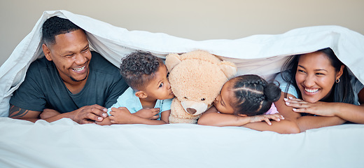 Image showing Black family, bed and teddy bear with parents and kids kissing a stuffed animal while lying together in a bedroom. Portrait, love and children inside to relax in the morning with mother and father