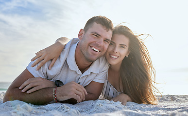 Image showing Portrait, love and relax couple, beach and holiday in summer sunset. Happy woman hug her joyful man while lying in sand at the seashore on vacation or Boyfriend and girlfriend enjoy ocean travel