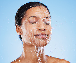 Image showing Woman, shower and water splash on face for skincare hydration or clean hygiene against blue studio background. Female in facial wash with water to hydrate or cleanse for hygienic body care treatment