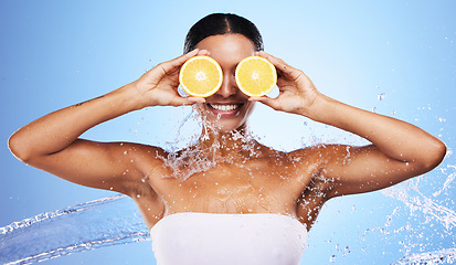 Image showing Black woman, water splash and orange skincare for natural beauty routine, organic skin health and vitamin c detox treatment. Happy smile, facial cleaning spa and advertising mockup on blue background