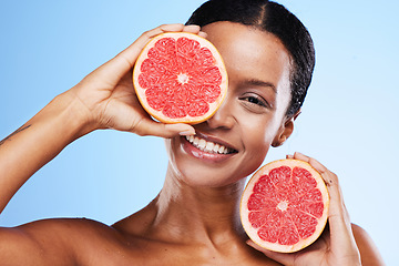 Image showing Black woman, fruit and smile in healthy skincare holding grapefruit for nutrition against a blue studio background. Portrait of happy African American female in vitamin C facial or cosmetic treatment