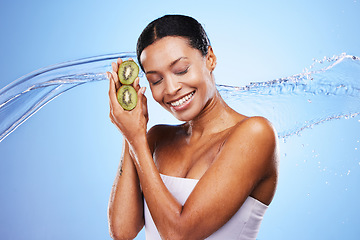 Image showing Skincare, beauty and kiwi with a water splash and black woman with a smile on a blue studio background for hydration, self care and dermatology. Happy model with omega 3 and vitamin c for skin glow