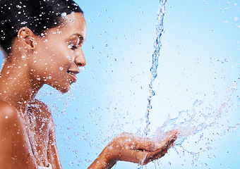 Image showing Water, splash and black woman doing skincare for health, wellness and hygiene in a studio. Beauty, shower and girl model doing a natural treatment for skin, body or face with aqua by blue background.