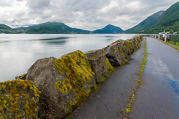 Image showing Mossy stones on a breakwater with mountains and sea