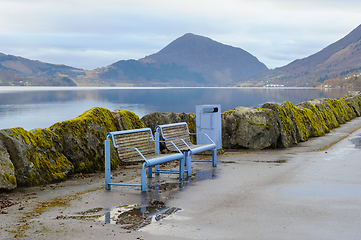 Image showing blue benches by mossy stones on the breakwater