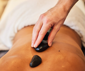 Image showing Hands, back and rock massage at spa for stress relief, relaxation and spiritual zen treatment at a resort. Hand of therapist applying hot rocks or stone to skin for body care, healing or wellness