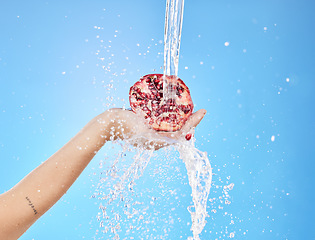 Image showing Water, splash and pomegranate with hands of woman for health, antioxidant and nutrition. Summer, organic and fruit with girl model for vitamin c for diet, food and clean detox in blue background