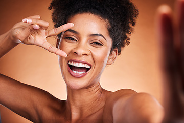 Image showing Black woman, peace sign and skincare beauty, selfie for wellness and natural makeup or cosmetics in studio background. A happy model with afro, face cosmetic, hand icon and self love empowerment