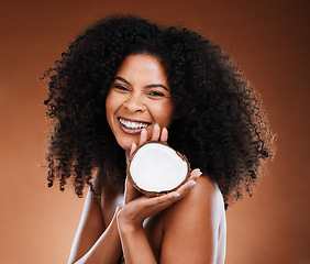 Image showing Skincare, hair care and black woman marketing coconut for wellness of skin against a brown studio background. Advertising, cosmetics and face portrait of an African model with fruit for beauty