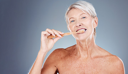 Image showing Brushing teeth, portrait and senior woman in studio for dental, mouth and tooth wellness with product marketing, advertising and promotion space. Elderly model with toothbrush for morning care mockup