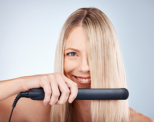 Image showing Hair care, flat iron and woman advertising beauty product, cosmetics and smile on grey mockup studio background. Happy female model, healthy hair and wellness with electronic device or technology