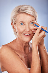 Image showing Beauty, makeup and eyeliner with a senior woman in studio on a gray background to apply cosmetics to her face. Eyes, product and luxury with a mature female applying a cosmetic with an eye pencil