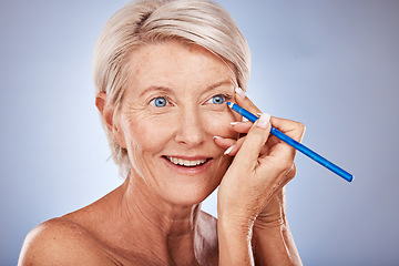 Image showing Face, beauty and eyeliner with a senior woman in studio on a gray background to apply cosmetics. Makeup, beautiful and eye pencil with a mature female applying a cosmetic product to her face