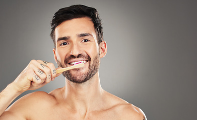 Image showing Brushing teeth, bamboo and man in studio for dental, dentist and mouth wellness with product promotion on mockup space. Model portrait with wood and eco friendly toothbrush for mint fresh breath