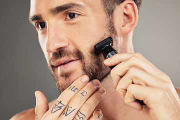 Image showing Shaver, beard and man grooming in a studio for beauty, hygiene and skincare for wellness. Health, shave and healthy guy shaving his facial hair with a cosmetic razor isolated by a gray background.