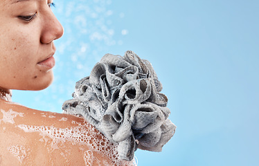 Image showing Shower, cleaning and loofah with a woman in studio on a blue background for water hydration or hygiene. Skincare, wellness and beauty with a female washing in the bathroom for luxury body care