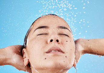 Image showing Face, skincare and woman in shower in studio isolated on blue background. Hygiene, water splash or healthy female model from Canada cleaning, bathing and washing for body care, beauty or wellness