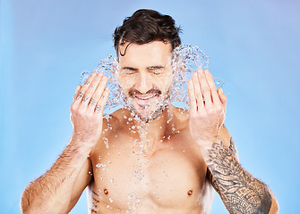 Image showing Health, skincare and water splash, man on studio background happy and topless with tattoo washing face. Smile, wellness and clean water, guy with muscles, healthy mindset and body care lifestyle.