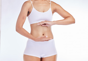 Image showing Hands, body and health with a model woman frame her stomach in studio on a gray background for wellness. Weightloss, tummy and diet with a female posing to promote healthy eating or nutrition