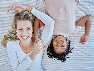 Image showing Top view, family and mother with foster girl on bed, relaxing and bonding. Love, care and adoption portrait of happy mom with black kid in bedroom, smiling and enjoying quality time together in house