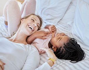 Image showing Happy, adoption and mother relaxing with her child on a bed while talking, laughing and bonding. Happiness, love and mom telling her girl kid a comic joke while lying in the bedroom together at home.