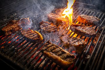 Image showing Beef steaks on the grill with flames.
