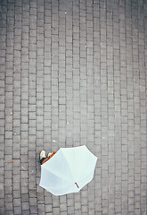 Image showing Top view, rain and person with umbrella in city, street or urban road mock up. Travel, freedom and pedestrian with parasol on asphalt in winter weather traveling, standing or enjoying time outdoors