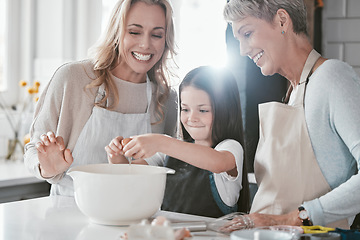 Image showing Baking, excited and girl with mother and grandmother in the kitchen cooking as a team. Food, teamwork and child with mom and senior woman learning to crack an egg while helping with dinner in a house