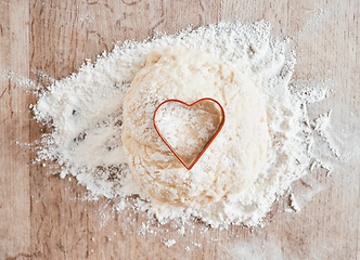 Image showing .Bakery flour in kitchen, wood texture table and cooking dessert with heart cookie cutter. Love pastry in wheat cake dough, recipe for baking pizza bread and love language to bake food on weekend.