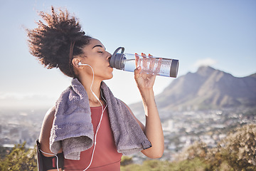 Image showing Music, workout and woman drinking water after exercise at sunrise along mountain, wellness and training on blue sky. Radio, water and black woman stop for break from fitness, running and cardio run