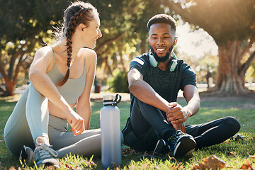 Image showing Couple, exercise and relax on grass in nature park for fitness rest, water hydration and interracial health discussion. Diversity, friends conversation and healthy cardio training break together