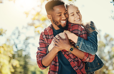Image showing Love, nature and diversity couple hug on outdoor journey together, romantic park date and quality time fun. Sunshine flare, leaf and summer freedom peace for happy gen z woman and black man bonding