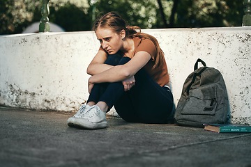 Image showing University, sad and woman student sitting outside in depression for fail on education exam. College, depressed and upset female sit on floor outdoors upset about educational learning book